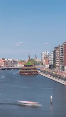 Sudaki pagoda biçiminde bir Çin restoranının hava manzarası, tarihi şehir merkezi binaları ve modern mimari zaman aralığının zeminine göre ayarlanmış. Amsterdam, Hollanda
