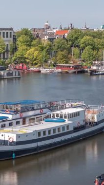 Oosterdok Limanı 'ndaki iskelede botları olan Amsterdam gökyüzü manzarası. Amsterdam Centraal İstasyonu ve Scheepvaarthuis yakınlarındaki geleneksel Hollanda mimarisi. Amsterdam, Hollanda