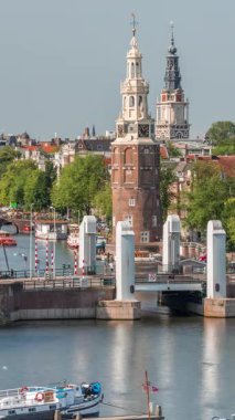 Amsterdam şehri, Montelbaanstoren Kulesi 'nin yer aldığı, kanal boyunca uzanan şehir manzaralı bir zaman çizelgesi. Eski kentteki tarihi Hollanda evleri, köprüler, mavnalar ve yüzen evler