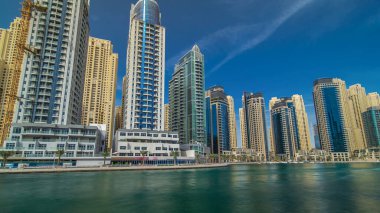 Dubai Marina Kuleleri, Birleşik Arap Emirlikleri 'ndeki gezinti güvertesi zaman aşımından suya yansıdı. Dubai Marina, Dubai 'de yer alan bir şehirdir. Mavi bulutlu gökyüzü