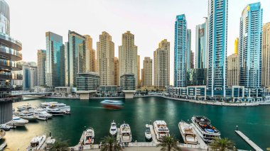 Modern binaları ve geleneksel tekne saatleri olan Dubai marinası. Günbatımı saatinde yukarıdan modern kulelerin en üst hava manzarası
