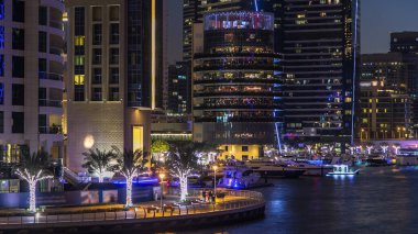 Dubai Marina rıhtımı kuleleri, rıhtımda restoranları ve Dubai 'deki köprüden geceye geçiş zamanı, Birleşik Arap Emirlikleri. Gün batımından sonra yapay kanallı bölge