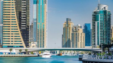Dubai Marina modern kuleleri ve yüzen yatları ve gezinti güvertesinden botları olan köprü, Birleşik Arap Emirlikleri. Gökdelenlerin en yükseği. Mavi gökyüzü