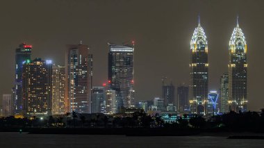 Geceleri Palm Island 'dan ışıklandırılmış kuleleri olan Dubai İnternet Şehri bölgesi.