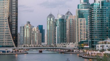Dubai Marina rıhtımı, Dubai 'deki köprüden gece vardiyasına kadar uzanan kuleleri ve yatları olan Birleşik Arap Emirlikleri. Çevresinde yapay kanallar ve aydınlık gökdelenler olan bir bölge.