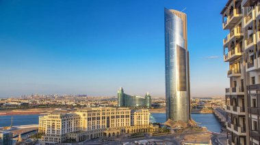 Business Bay yakınlarındaki modern kule Dubai Deresi üzerindeki köprüden geçiyor. Gün batımından önce mavi bulutlu gökyüzü ve havaalanı manzarası. Güneş yansımalı gökdelen