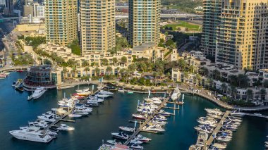 Dubai Marina gezinti güvertesi ve kanalı gündüz vakti Dubai, BAE 'de yüzen yat ve teknelerle hava görüntüsü. Modern kuleler ve yoldaki trafik