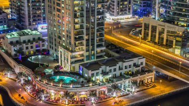 Dubai Marina yürüyüş alanının gece hava manzarası. Dubai, BAE 'de yüzen yatları ve tekneleri olan restoranlar ve kanallar var. Köprüde ışıkları ve trafiği olan modern kuleler.
