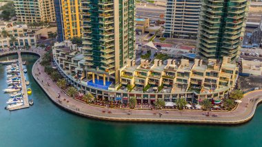 Dubai Marina gezinti güvertesi ve kanalı gündüz vakti Dubai, BAE 'de yüzen yat ve teknelerle hava görüntüsü. Günbatımından önce yollarda modern kuleler ve trafik
