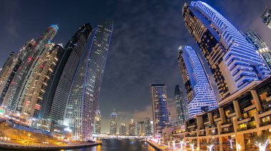 Dubai Marina rıhtımı. Köprüden gece, gündüz kuleleri ve yatları var. Geçiş zamanı, Birleşik Arap Emirlikleri. Gökdelenler gün batımından sonra manzaraya bakar. balık gözü merceği