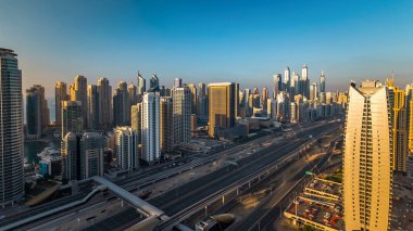 Dubai Marina ve Dubai, BAE 'deki JLT gökdelenlerinin günbatımı zaman çizelgesinde. Modern kuleler ve Şeyh Zized yolu üzerindeki trafik