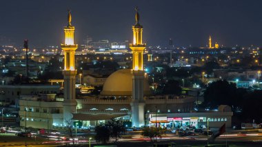Dubai 'nin gökdelenleri gece aydınlatılmış camii ve tepeden bakıldığında zaman dilimi yakınındaki dükkanlar. Dubai, Birleşik Arap Emirlikleri.