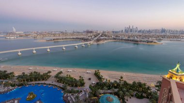 Dubai, BAE 'de gün batımından sonra Jumeirah Palm Island havalimanı. Villalar ve raylı tren yukarıdan görünüyor. Jumeirah Palm Dubai 'de arka planda gökdelenleri olan yapay ve benzersiz bir adadır..
