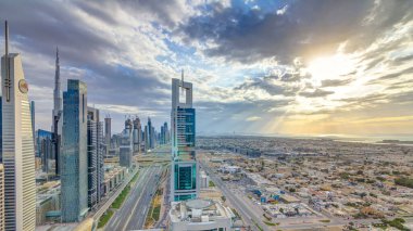 Dubai gökdelenleri, gün batımı akşam vakti. Dubai metro istasyonu ve Şeyh Zayed Yolu 'ndaki trafik. Kule çatısından gökyüzü görüntüsü. Güzel renkli bulutlu gökyüzü ve güneş ışığı