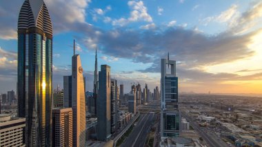 Dubai gökdelenleri akşam saatlerinde güneş camlarında yansıyor. Dubai metro istasyonu ve Şeyh Zayed Yolu 'ndaki trafik. Kule çatısından gökyüzü görüntüsü. Renkli bulutlu gökyüzü ve güneş ışığı