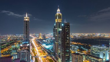 Dubai şehir merkezinde mimarlık gecesi zaman aşımı. Şeyh Zayed yolu üzerinde, finans bölgesinde ve trafikte aydınlık gökdelenleri olan hava manzaralı bir yer. Uzun kuleler ve bulutlu gökyüzü