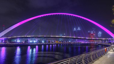 Dubai Su Kanalı gecesinde Dubai Deresi 'ni Jumeirah Sahili' ne bağlayan Dubai, Downtown Dubai ve Safa Parkı 'ndan geçen yaya köprüsü. Gökdelenlerin silueti. Birleşik Arap Emirlikleri