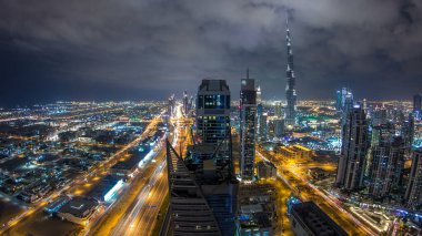 Dubai 'nin panoramik silueti gece zaman çizelgesi, Birleşik Arap Emirlikleri. Aydınlatılmış gökdelenler kule çatısı manzaralı. Güzel bulutlu gökyüzü. Renkli seyahat ve iş geçmişi