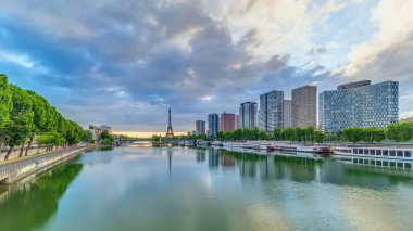 Eyfel Kulesi, Seine Nehri 'nde ve Fransa' nın Paris şehrinde teknelerle gün doğumu zamanı. Mirabeau Köprüsü 'nden gökyüzü dramatik bir şekilde görünüyor. Modern binalar ve yol trafiği. Özgürlük Anıtı