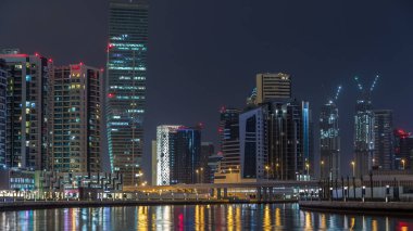 Dubai iş defne gece timelapse kuleleri. Bazı görünüm gökdelenler ve yapım aşamasında yeni kuleleri aydınlatılmış. Kanalı'nın su yansımalar. Köprüdeki trafik