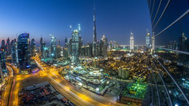 Dubai Şehir Merkezi 'nden geceye geçiş zamanı. Geceleri büyük, fütüristik şehir üzerinde hava manzarası. Dubai 'nin gökdelenleri camdan yansıyor, Birleşik Arap Emirlikleri. Akşam gökyüzü çatıdan yükseliyor