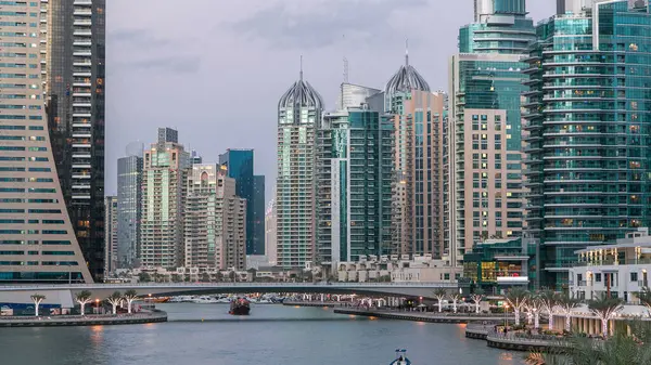 Dubai Marina rıhtımı, Dubai 'deki köprüden gece vardiyasına kadar uzanan kuleleri ve yatları olan Birleşik Arap Emirlikleri. Çevresinde yapay kanallar ve aydınlık gökdelenler olan bir bölge.