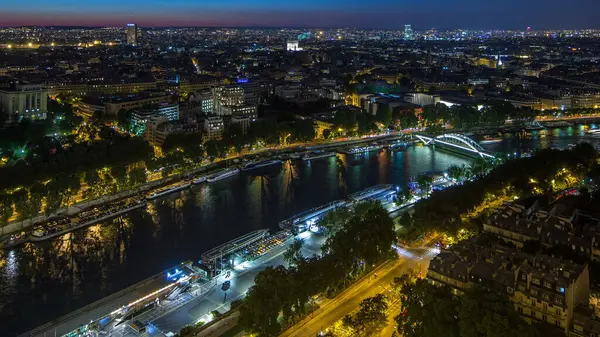 Paris City ve Seine nehrinin gece görüş açısı Eyfel Kulesi gözlem güvertesinin tepesinden geçen teknelerle dolu. Akşam aydınlatması. Yollarda trafik