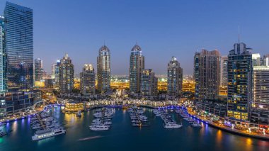 Dubai Marina gökdelenleri hava gününden geceye geçiş zamanı panorama, lüks yatları ve marina gezinti güvertesi olan liman, Dubai, Birleşik Arap Emirlikleri. Aydınlatılmış kuleler ve yol trafiği