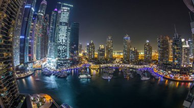Gece vakti Dubai Marina panoramik zaman çizelgesi, parlak ışıklar ve açık bir akşamda en yüksek gökdelenler. Aydınlatılmış kuleler, yatlar ve arka plandaki trafik