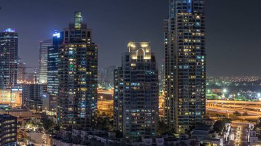Gece vakti Dubai Marina 'da pencerelerde parlayan ışıklar ve en yüksek gökdelenler. Aydınlatılmış kuleler ve arka plandaki trafik