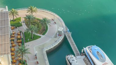 Meşhur Dubai Marina 'daki Cafe and Restaurant' ta modern liman sabah saatleri. Palmiyeli kaldırım ve su taksisi üst tarafı manzaralı. Marina - yapay kanal kenti