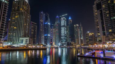 Dubai Yat Limanı defne yatların bir tekne timelapse hyperlapse. En yüksek gökdelenler gece ışıklı kanal suya yansıyan