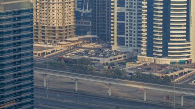 Sheikh Zayed yolundaki muhteşem çatı manzarası Dubai Marina ve JLT gökdelenlerini kuşattı. Gün batımında trafik ve metro hattıyla hava manzarası. Birleşik Arap Emirlikleri