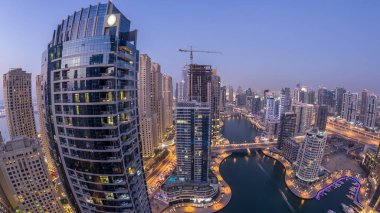 Dubai Marina gezinti güvertesi ve kanalı, gün batımından sonra Dubai, BAE 'de yüzen yat ve teknelerle panoramik hava manzaralı. Modern kuleler ve yoldaki trafik.