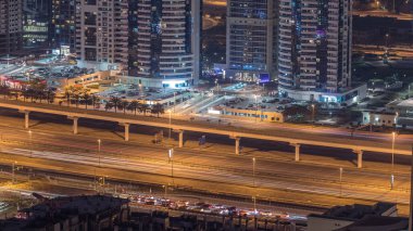 Sheikh Zayed yolundaki muhteşem çatı manzarası Dubai Marina ve JLT gökdelenlerini kuşattı. Geceleri trafik ve metro hattıyla hava görüntüsü. Birleşik Arap Emirlikleri