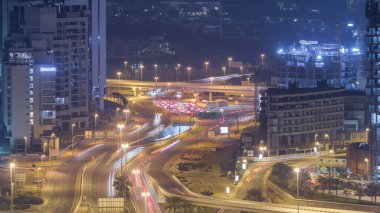 Bir büyük şehir gece timelapse bir yol kavşak hava görünümünü. Arabalar ve gökdelenler ile UAE Dubai Yat Limanı bölgesinin kentsel peyzaj.