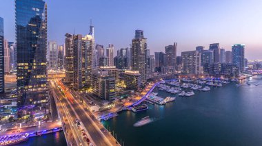 Dubai, BAE 'de gün batımından sonra yüzen yat ve teknelerle Dubai Marina gezinti güvertesi ve kanalı üzerinden geçen güzel bir gökyüzü çizgisi. Modern kuleler ve köprüdeki trafik.