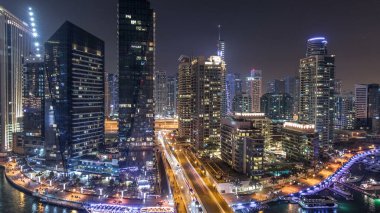 Su kanalı ve Dubai Marina manzarası, gece timelapse güvertede. Konut kuleleri aydınlatma ve aydınlatma ile. Yat ve tekne trafiği olan gökdelenler yüzen