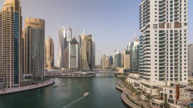 Gün batımında inanılmaz renkli Dubai marinası panoramik gökyüzü. Yatları ve tekneleri olan çok uzun gökdelenler için harika bir perspektif. Binaların üzerinde güneş ışığı. Birleşik Arap Emirlikleri.