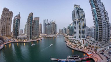 Hava üst görüntüsü, günden geceye geçiş zamanı. Dubai Marina gezinti güvertesi ve kanalı, gün batımından sonra Dubai, BAE 'de yüzen yatlar ve teknelerle dolu. Modern kuleler ve trafik