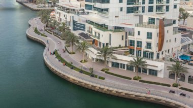 Dubai Marina 'daki gezinti güvertesi ve kanalı, lüks gökdelenleri ve yatları olan, Birleşik Arap Emirlikleri. Palmiyeli liman manzarası