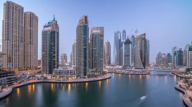 Dubai Marina gezinti güvertesi ve kanalı, gün batımından sonra Dubai, BAE 'de yüzen yat ve teknelerle hava görüntüsü. Modern kuleler ve trafik