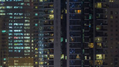 Gece timelapse, gökdelenlerin parlayan windows. Görünümü office yüksek katlı binalarda Dubai Yat Limanı ve modern konut. İnsanlar hareketli iç. Hava üstten görünüm.