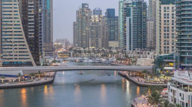 Dubai, BAE 'de gün batımından sonra yüzen yat ve teknelerle Dubai Marina gezinti güvertesi ve kanallarının havadan zamana güzel bir görüntüsü var. Modern kuleler ve yoldaki trafik.