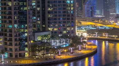 Su kanalı ve Dubai Marina manzarası, gece timelapse güvertede. Konut kuleleri aydınlatma ve aydınlatma ile. Yat ve tekne trafiği olan gökdelenler yüzen