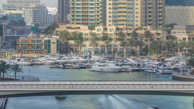 Dubai marinasındaki köprü, günbatımında ufuk çizgisi. Yatları ve tekneleri olan çok uzun gökdelenler için harika bir perspektif. Binaların üzerinde güneş ışığı. Birleşik Arap Emirlikleri.