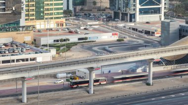 Jumeirah gölü yakınlarındaki metro istasyonunun hava görüntüsü. Gökdelenler, zaman çizelgeleri. Şeyh zayed yolunda trafik var. Çıkışa yakın otobüs durağı..