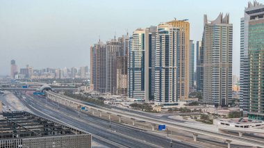 Şeyh Zayed yolu üzerindeki panoramik çatı manzarası Dubai Marina ve JLT gökdelenlerini çevreledi. Gün batımında trafik ve metro hattıyla hava manzarası. Birleşik Arap Emirlikleri