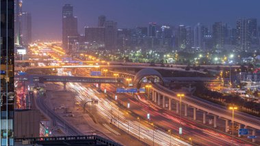 Jumeirah göl kulelerinin, gökdelenlerin ve Al Barsha bölgesinin gece gündüz geçiş zamanının havadan görüntüsü. Golf sahası ve metro hattı yakınlarındaki Şeyh Zized yolunda trafik var..