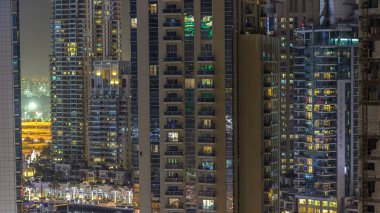 Su kanalı ve Dubai Marina manzarası, gece timelapse güvertede. Konut kuleleri aydınlatma ve aydınlatma ile. Yat ve tekne trafiği olan gökdelenler yüzen